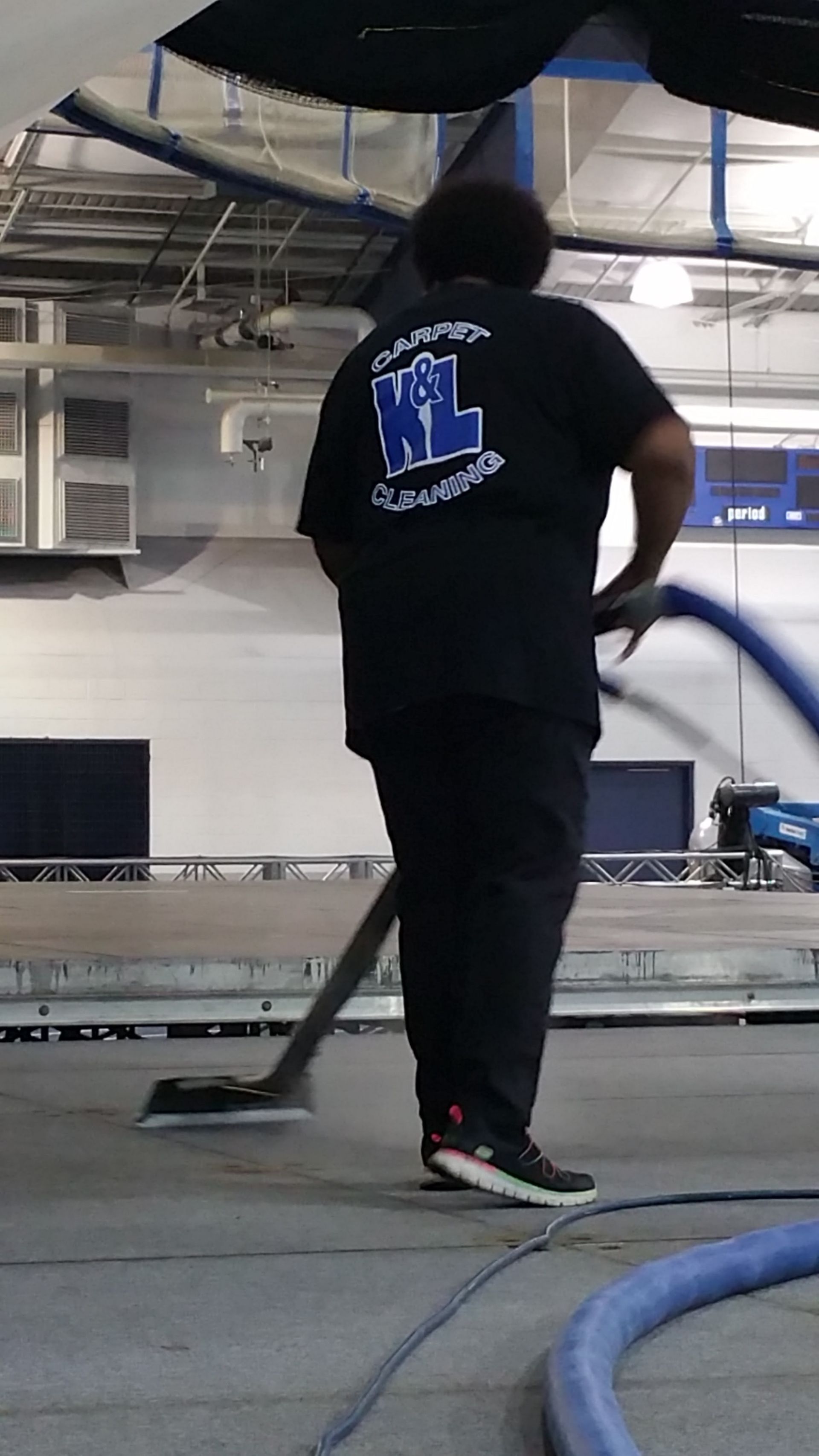 Man cleaning blue office carpet with an extraction machine, leaving a clean path.