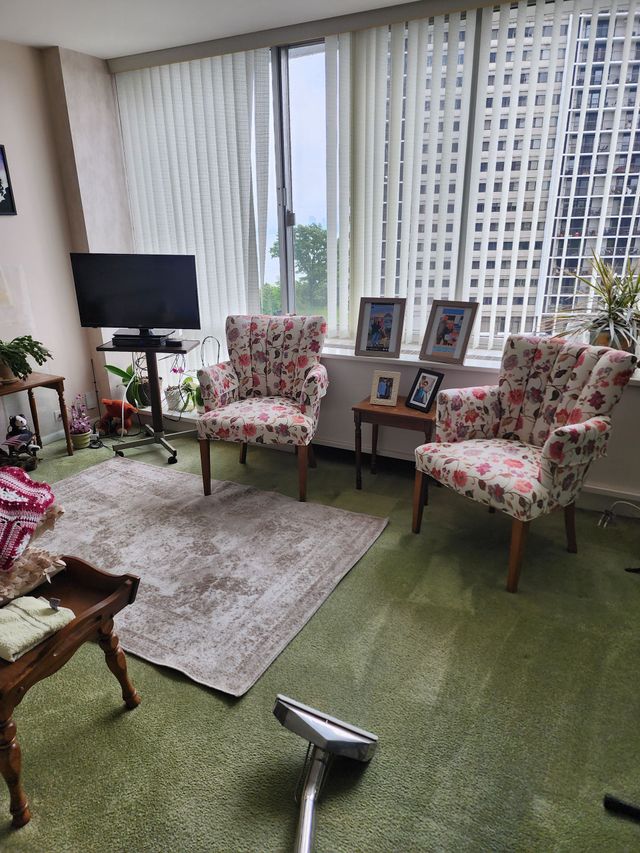 A modern office lounge with three orange cylindrical stools, teal seating, and a patterned carpet floor.