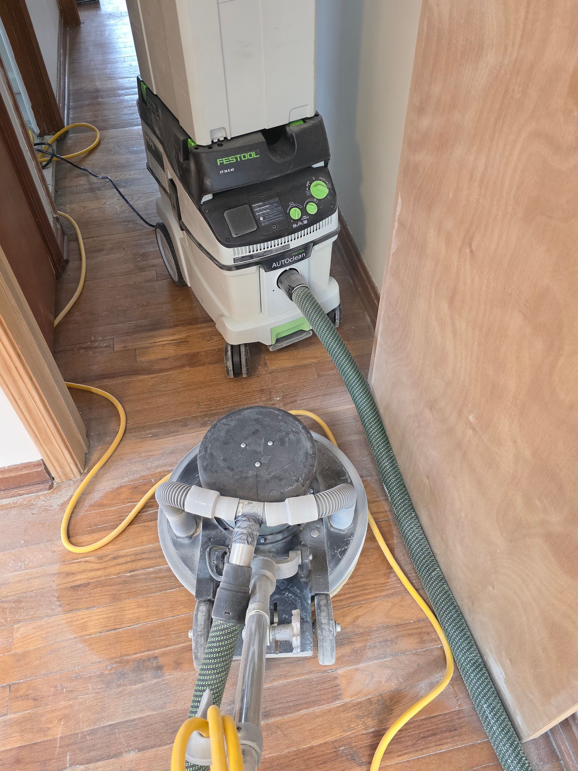 Two carpet cleaners with hoses in a narrow hallway, one black and white and one clear dome model.