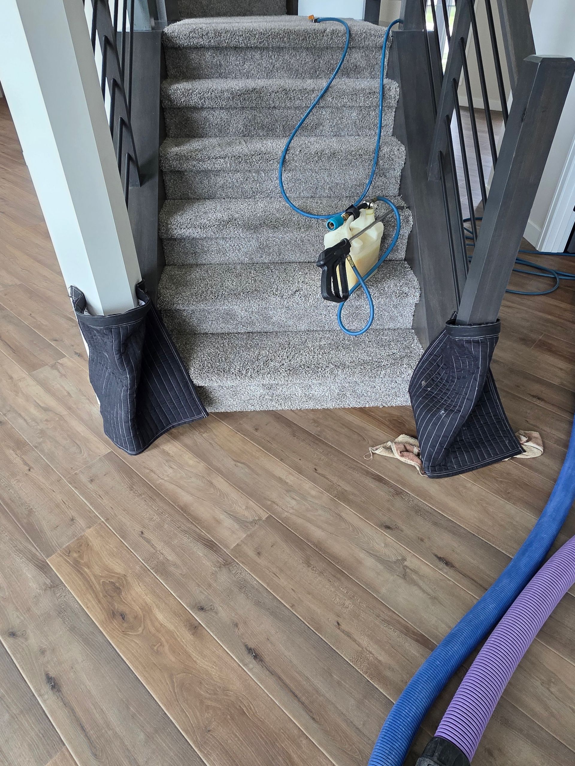 Carpeted stairs with a blue rope on a wooden floor and a cordless drill hanging near the steps