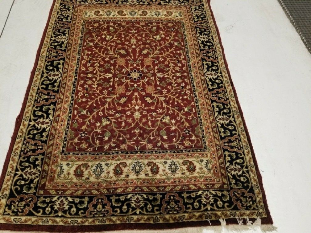 Red and black patterned area rug on a light floor, viewed from above
