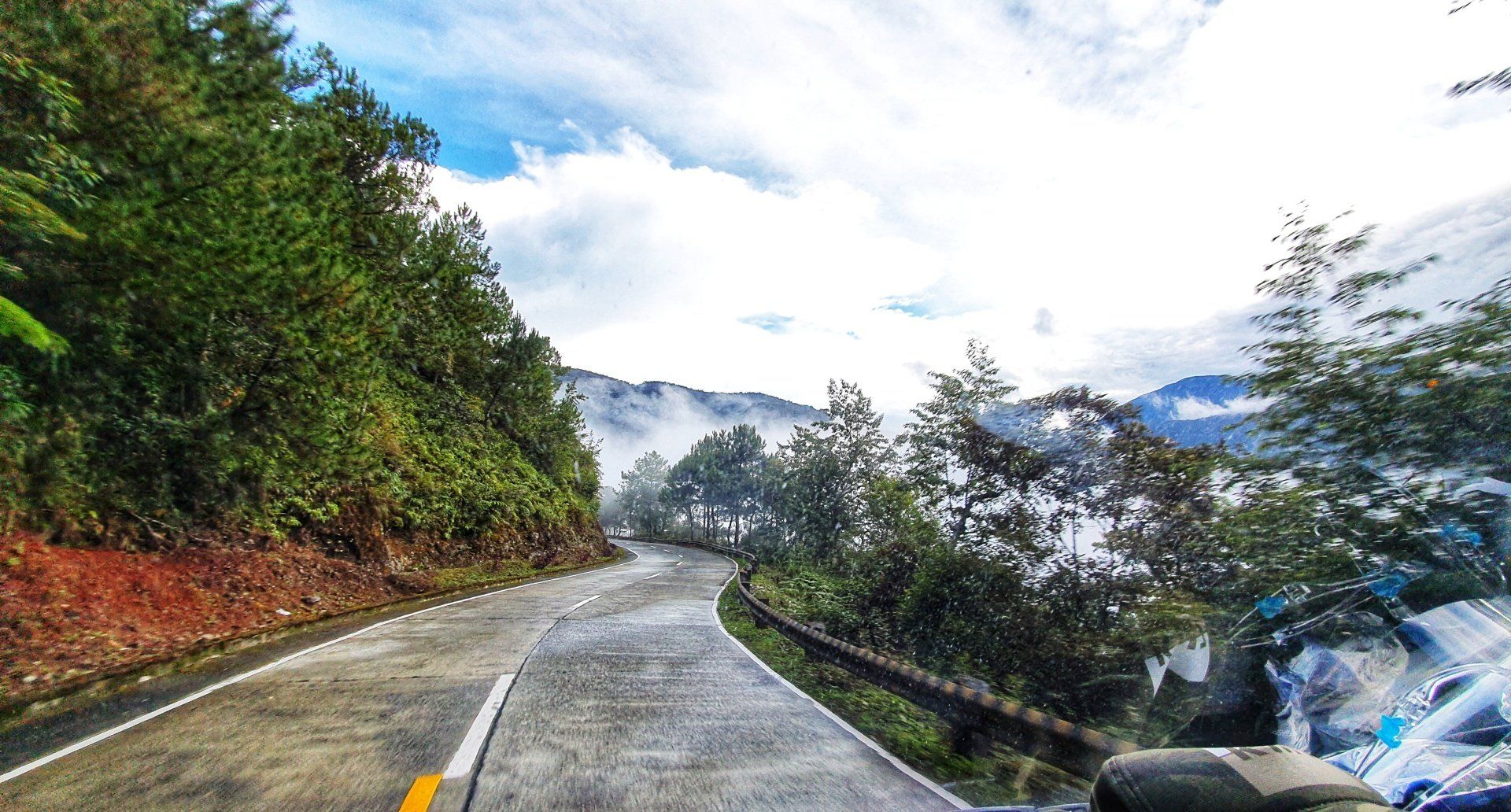A motorcycle is driving down a winding road surrounded by trees.