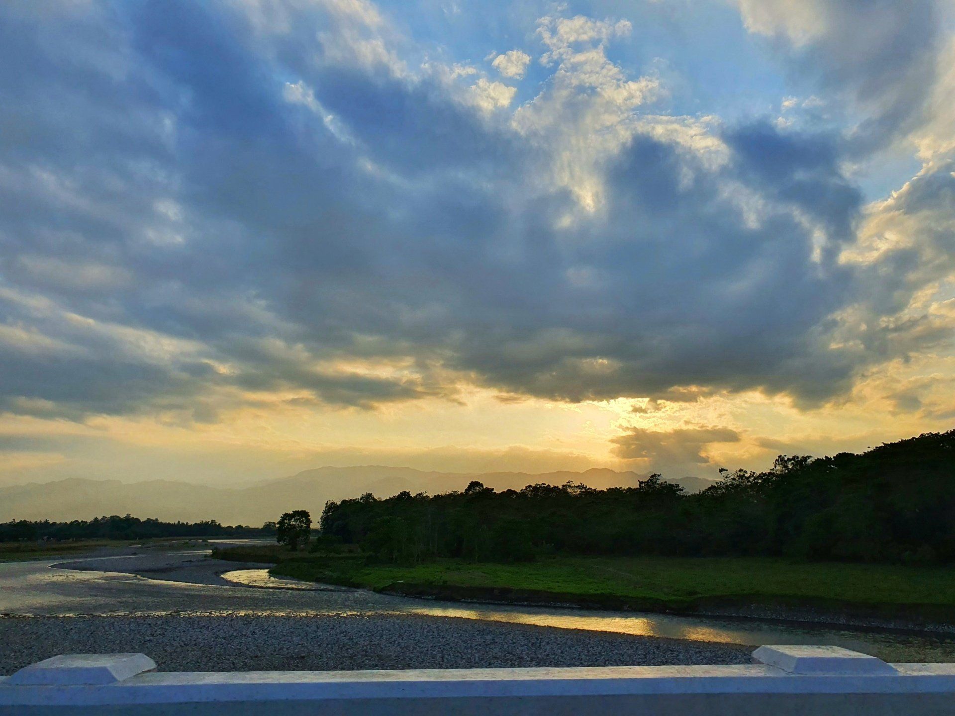 A bridge over a river with a sunset in the background.