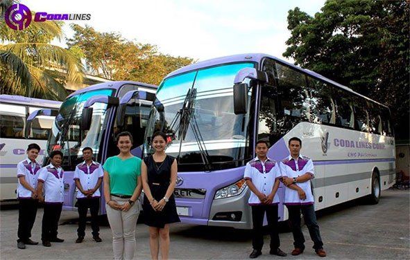 A group of people standing in front of a bus that says cobra lines
