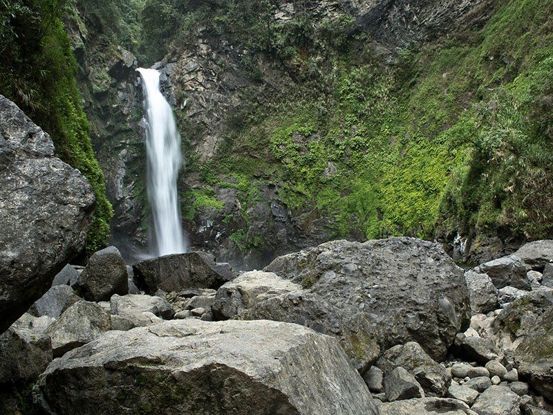 A waterfall is surrounded by rocks and trees