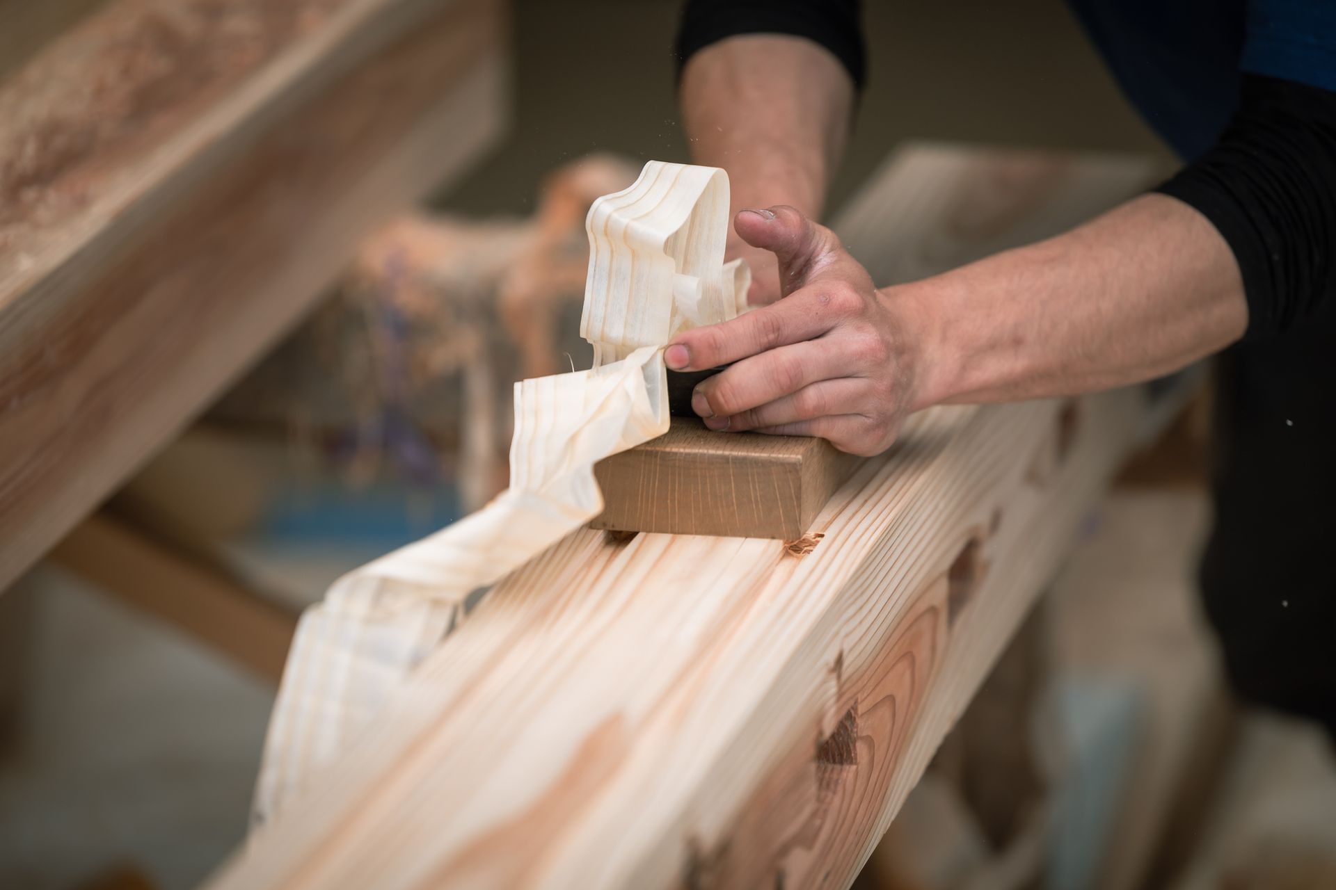 Hands planing wood beam, shavings curling. Hands planing wood beam, shavings curling.