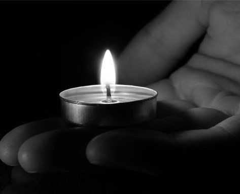 a person is holding a small lit candle in their hands