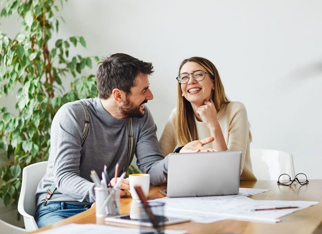 A man and a woman are sitting at a table with a laptop.
