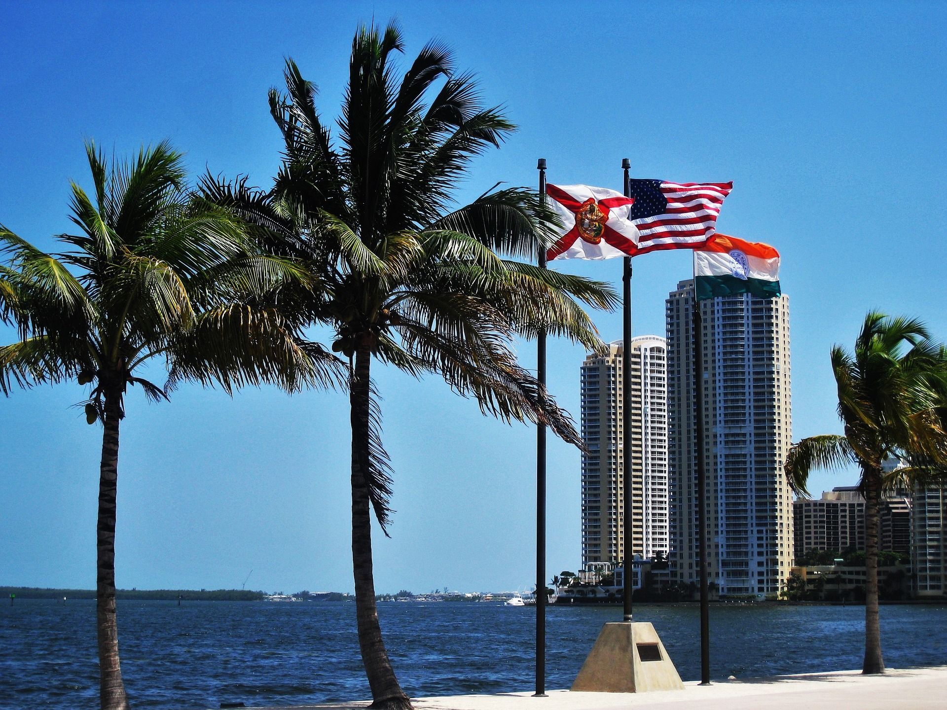 Two flags are flying in front of a body of water