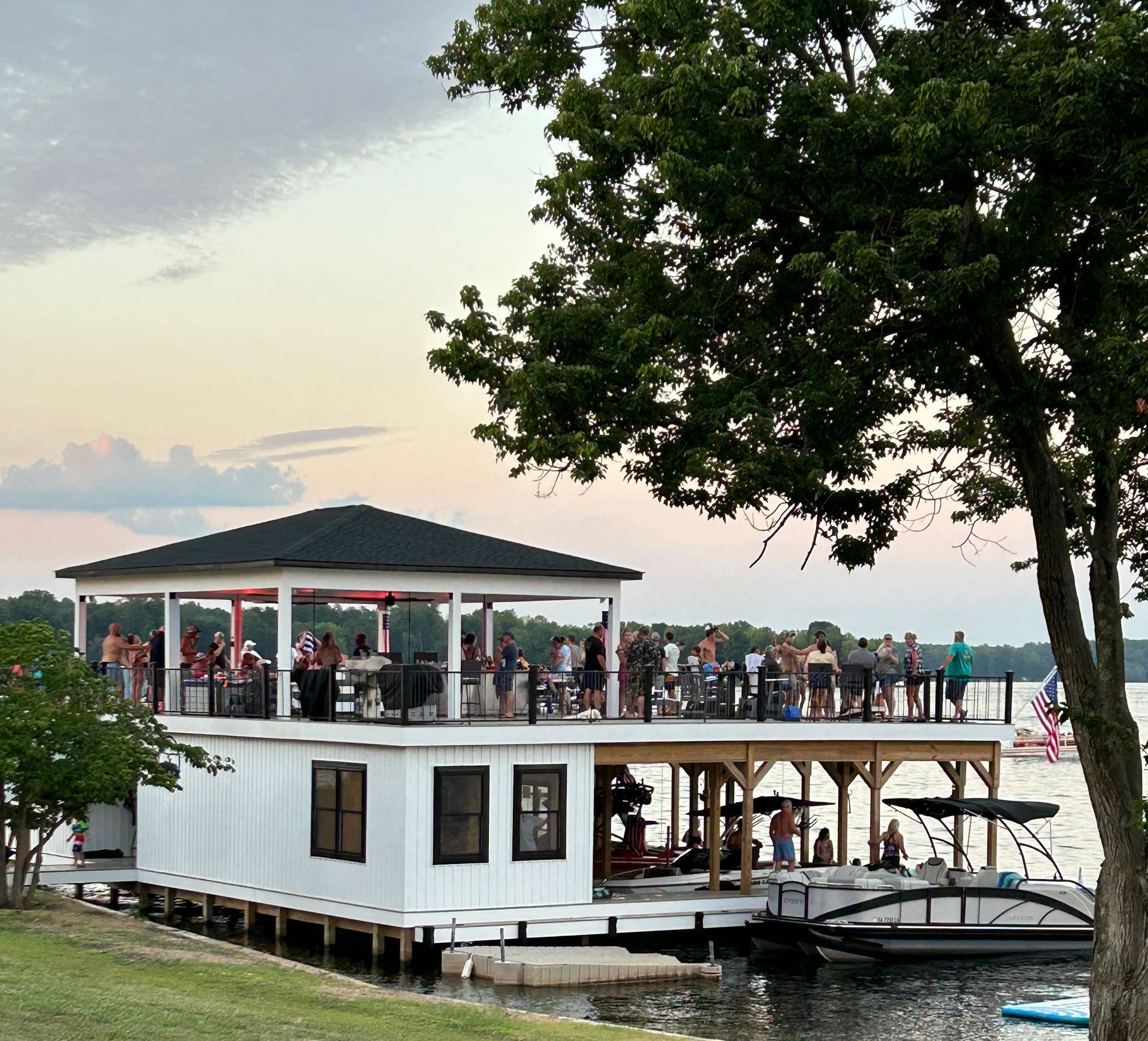A group of people are sitting on a dock next to a body of water.