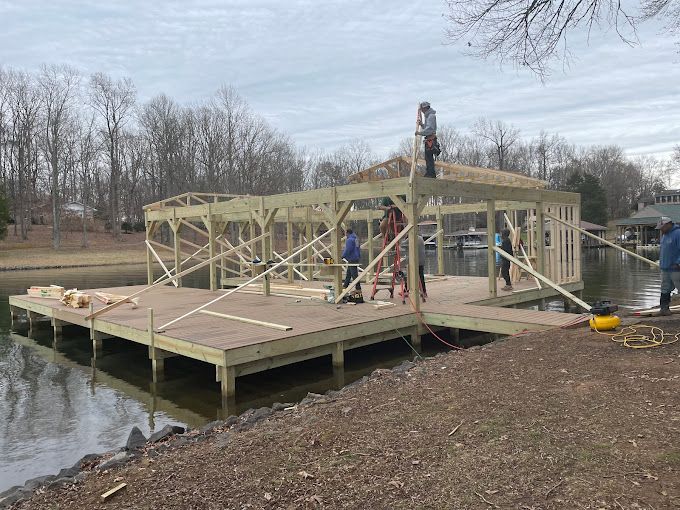 A group of people are working on a dock next to a body of water.