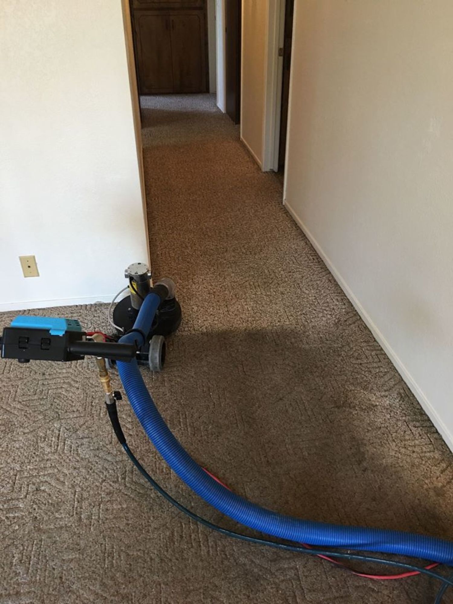 A vacuum cleaner is sitting on a carpet in a hallway.