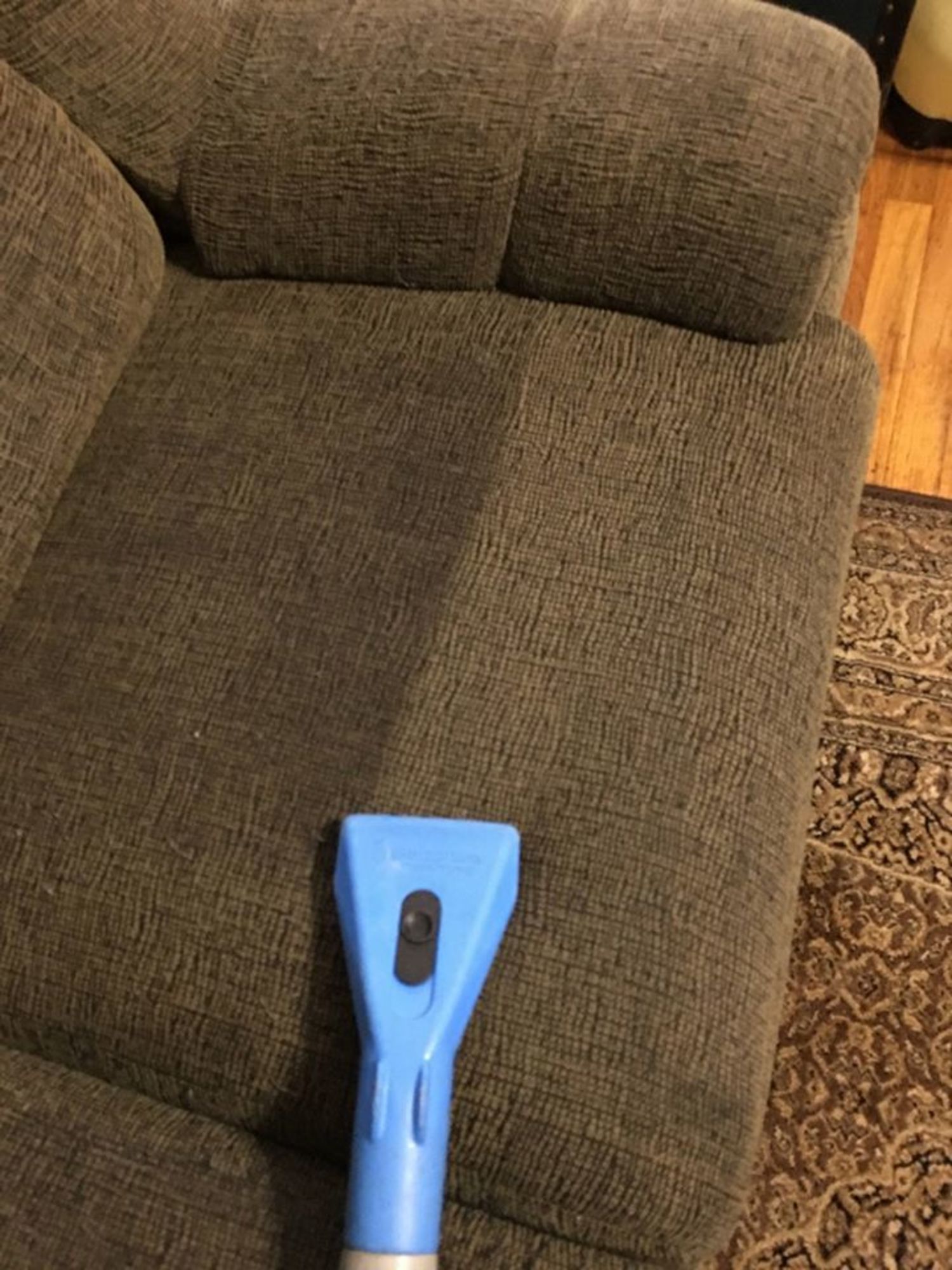 A blue vacuum cleaner is sitting on a couch in a living room.