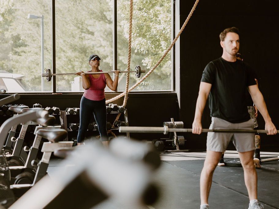 A man and a woman are lifting weights in a gym.