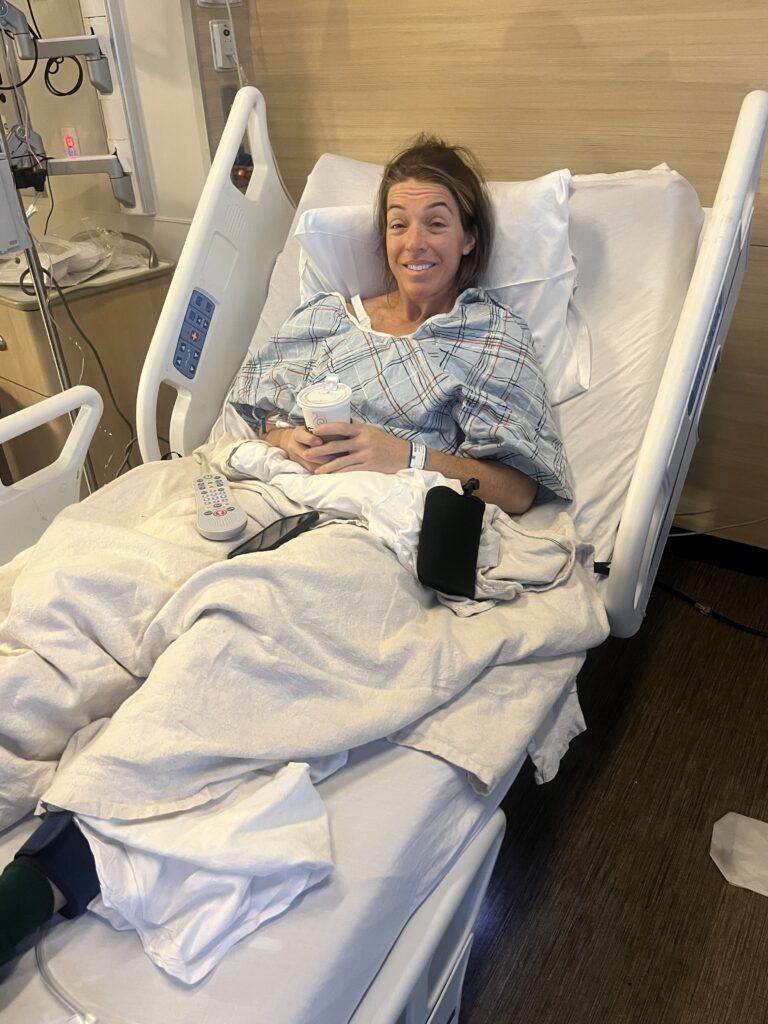 A woman is laying in a hospital bed and smiling.