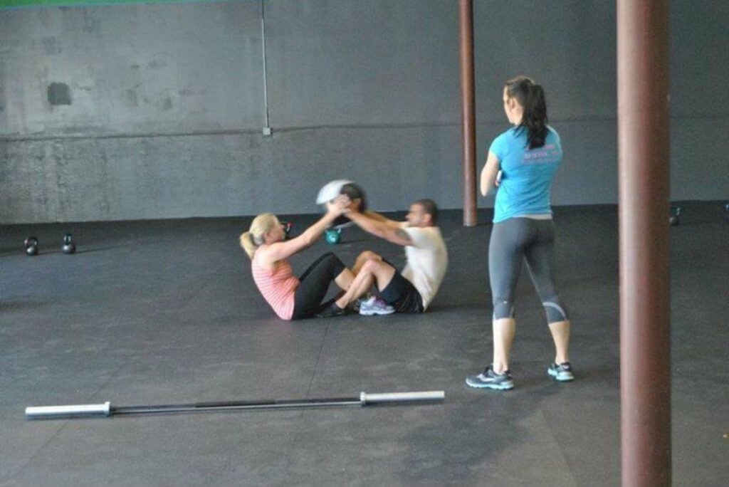 A woman in a blue shirt is taking a picture of people doing exercises