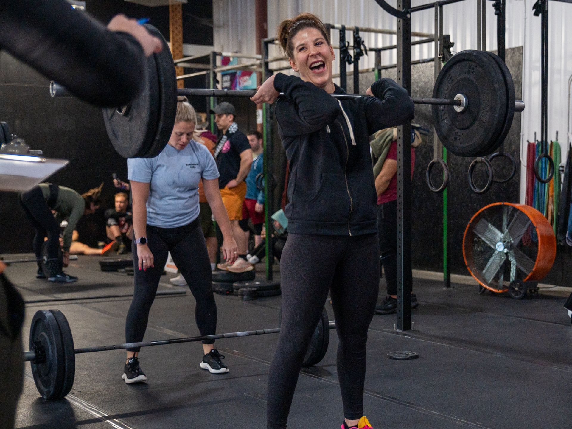 A woman is lifting a barbell in a gym.