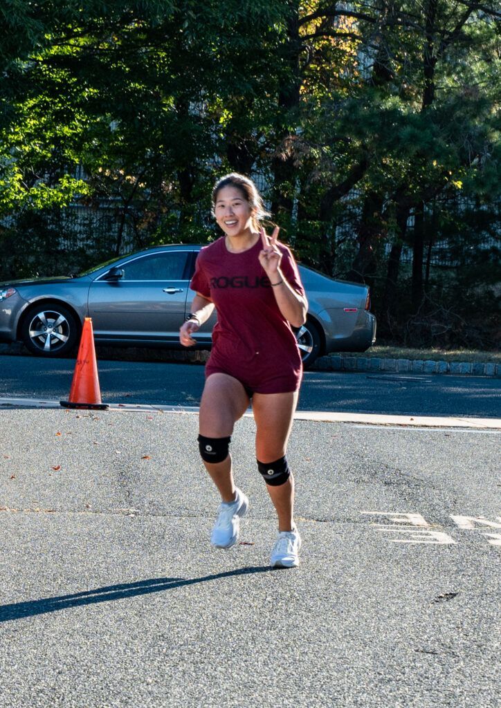 A woman is running down a street with a car in the background.