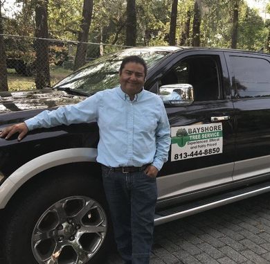 A man in a blue shirt leans against a black truck