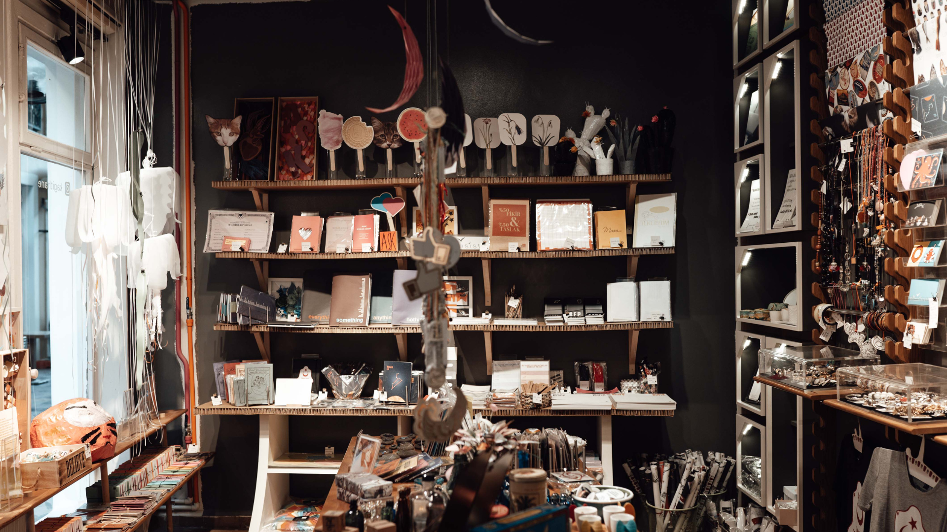 A shop interior with shelves displaying various art and gifts, featuring a dark wall backdrop.