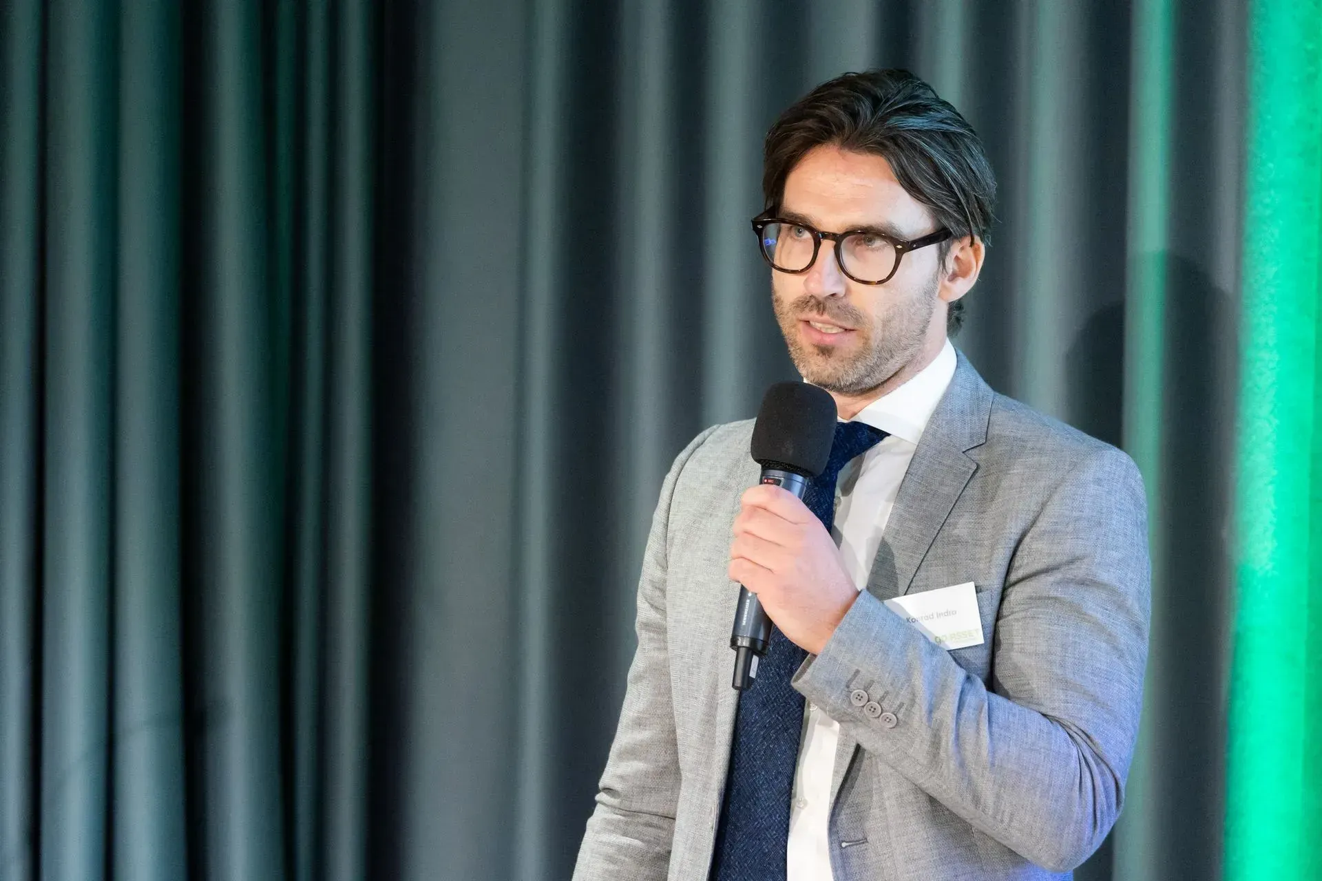 Ein Mann in Anzug und Krawatte hält ein Mikrofon.