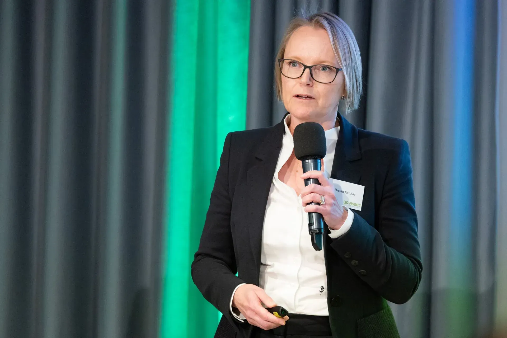 Eine Frau im Anzug hält ein Mikrofon und hält eine Präsentation.