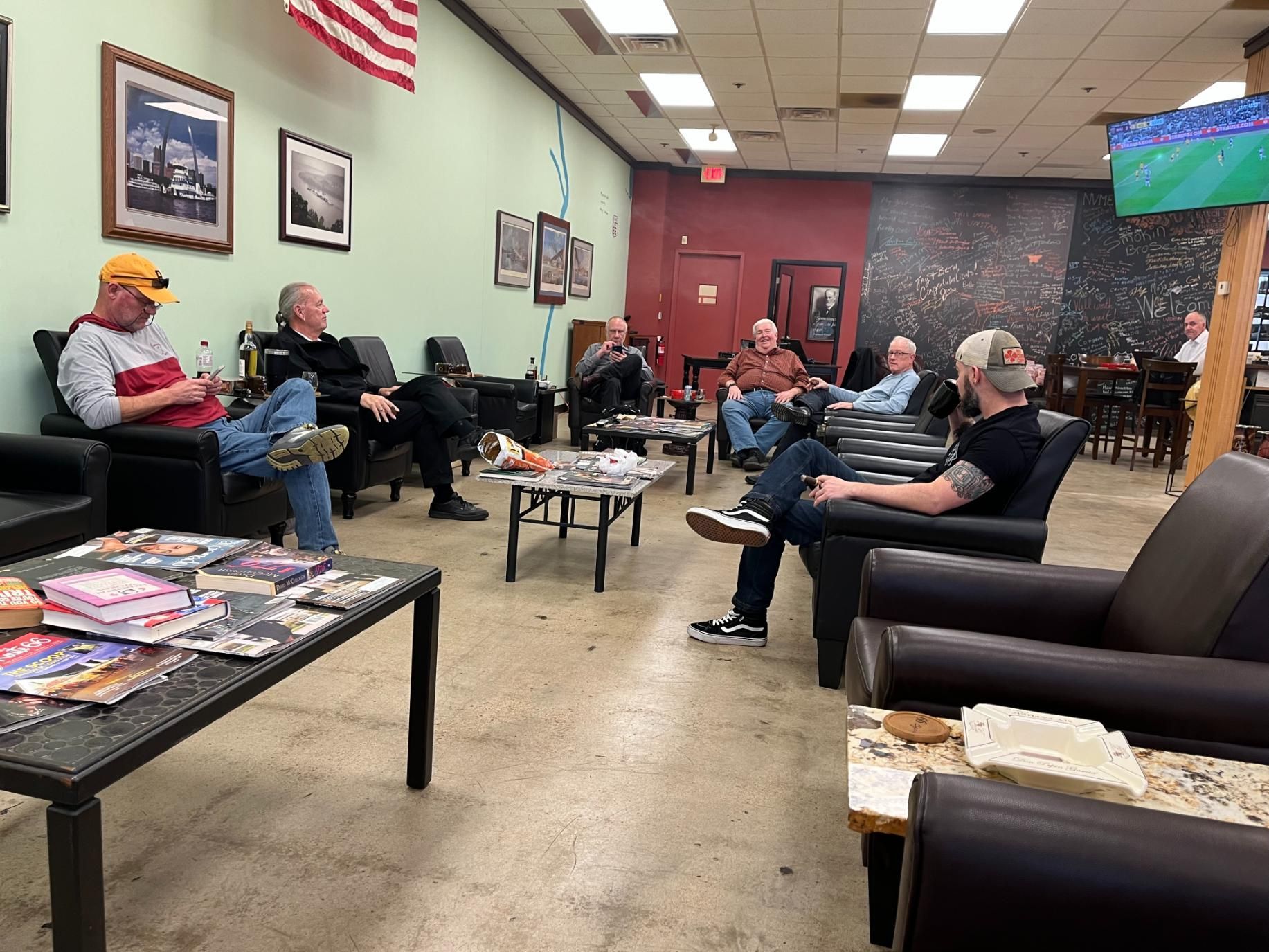 A group of men are sitting in chairs in a living room.