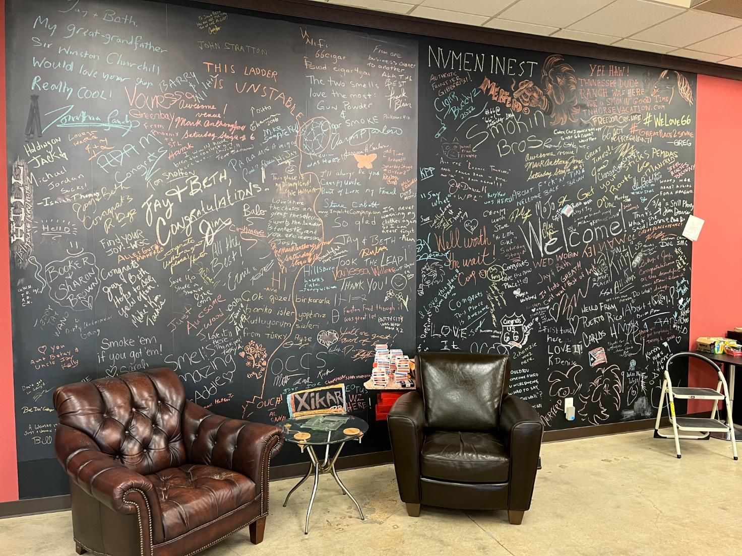Two chairs are sitting in front of a large chalkboard wall.