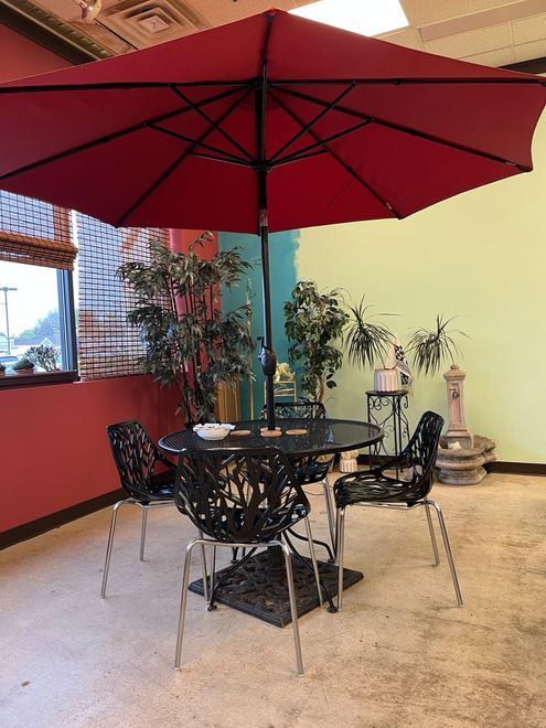 A table and chairs under an umbrella in a room.