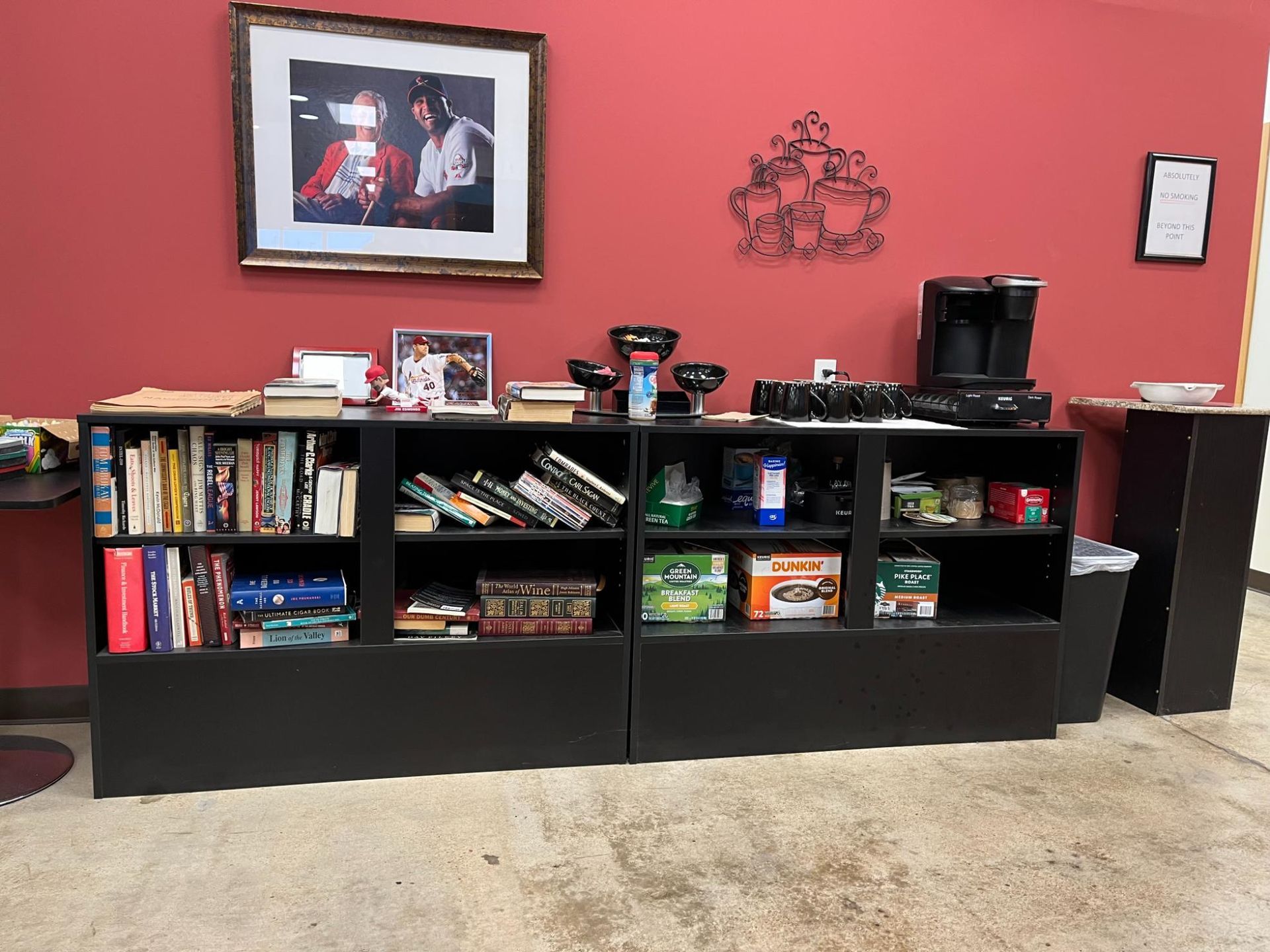 A shelf filled with books and a picture on the wall.