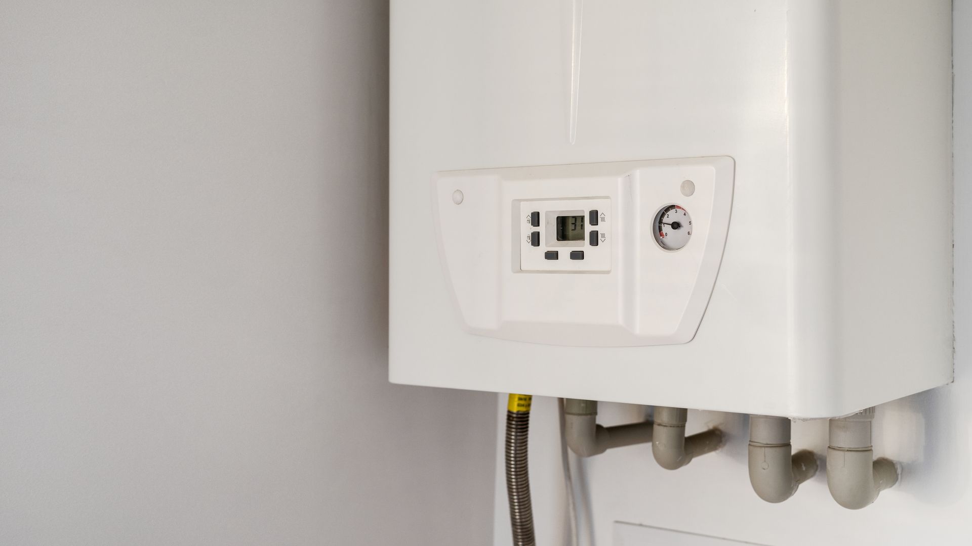 White wall-mounted gas boiler with a digital display and connected pipes.