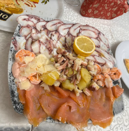 Piatto di frutti di mare con salmone affumicato, polpo, gamberi, patate, limone e scaglie di formaggio su un vassoio