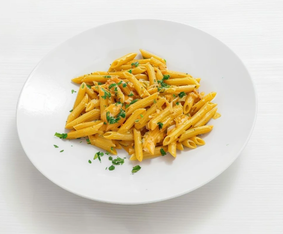 Piatto di penne al sugo di pomodoro con erbe aromatiche tritate, servito su un piatto bianco.