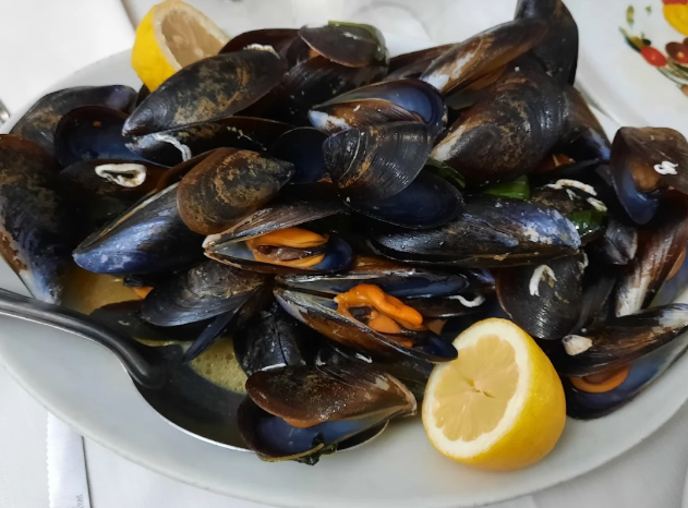 Piatto di cozze al vapore con spicchi di limone su un piatto bianco