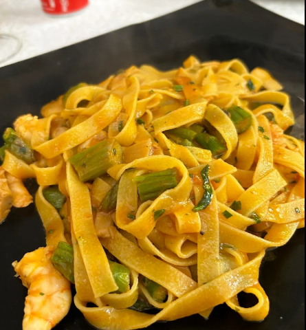 Tagliatelle con gamberi e verdure verdi su un piatto nero