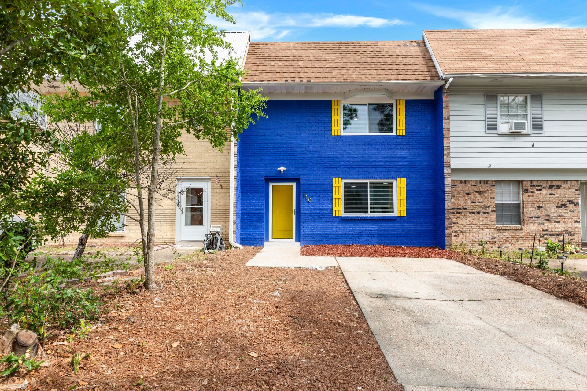 A blue house with yellow shutters and a yellow door