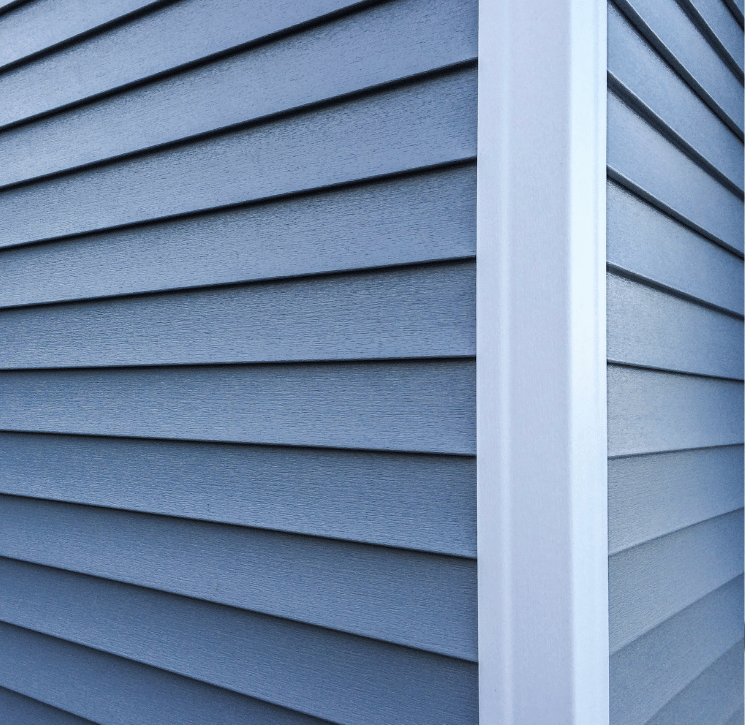Blue horizontal siding on a building's corner with a vertical white corner post.