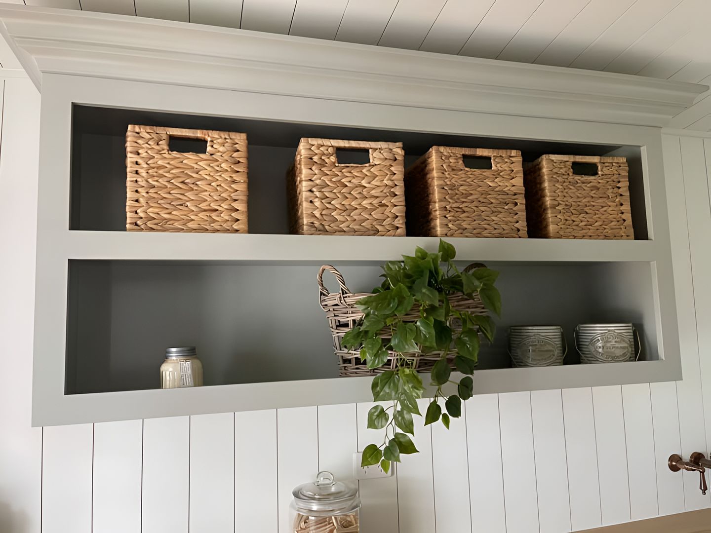 Built-in gray shelf with woven baskets, a plant, and jars.