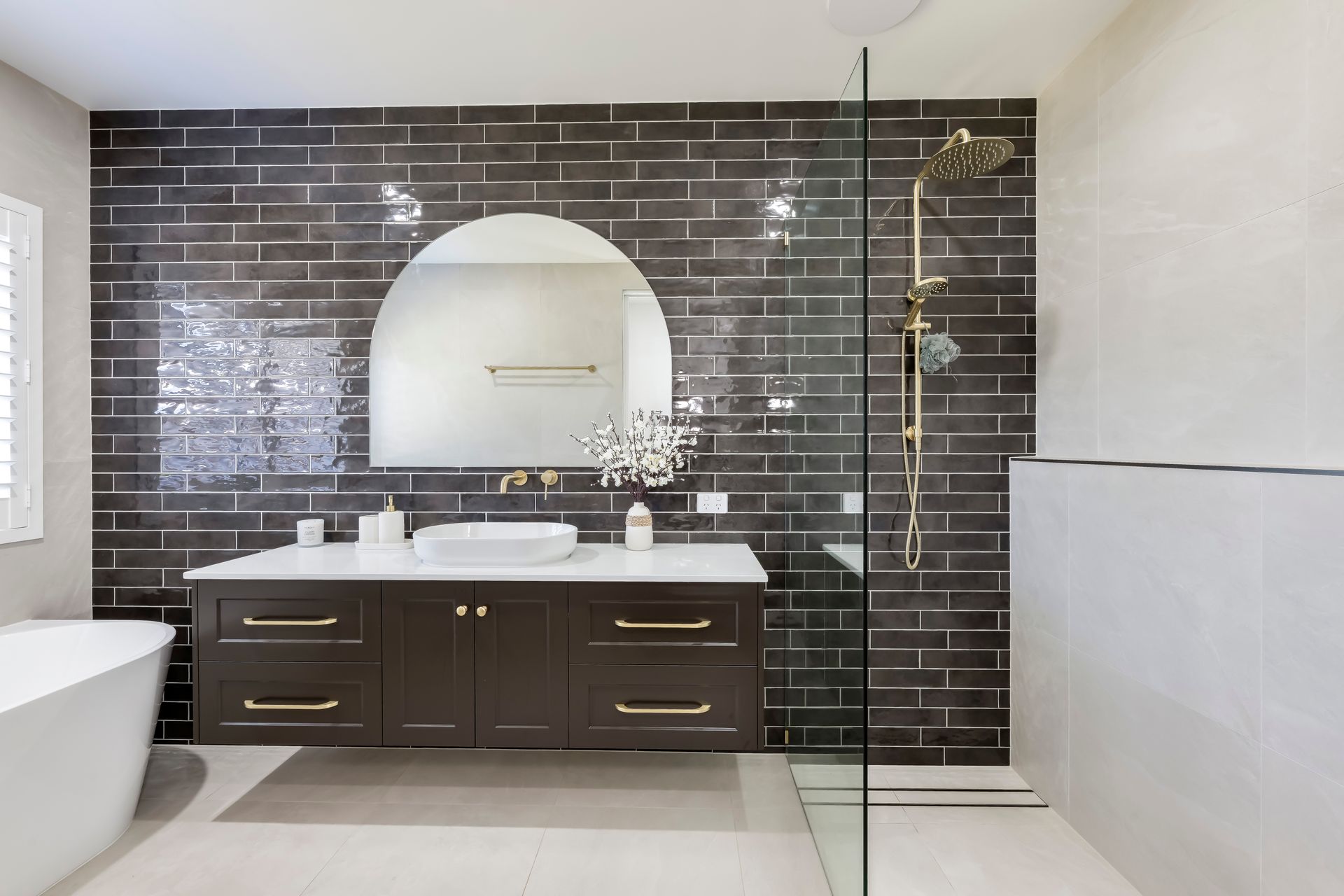 Modern bathroom with gray tiled walls, wooden vanity, and shower.