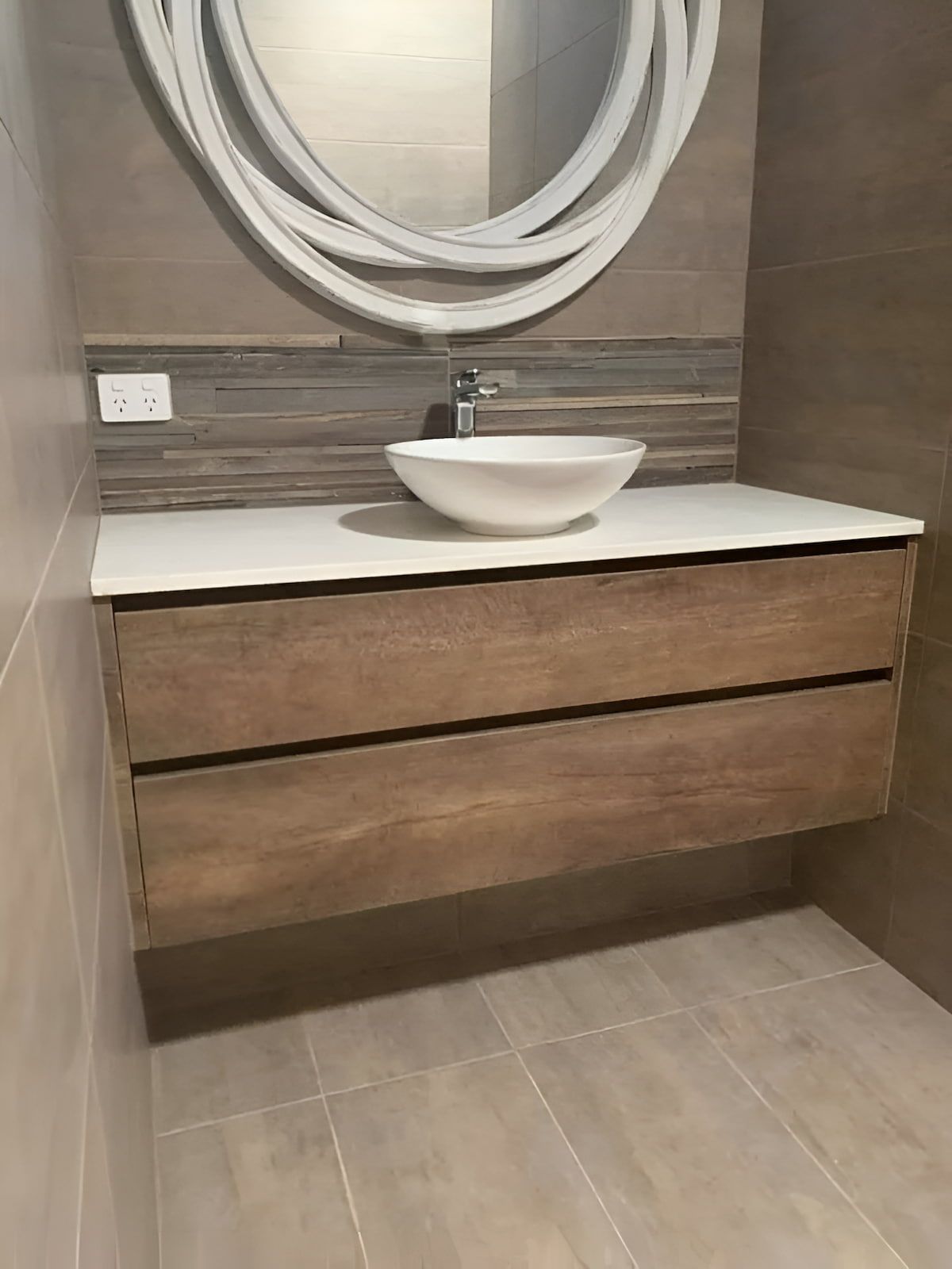 Floating Wooden Bathroom Vanity With White Countertop, Vessel Sink, And Round Mirror — Master Cabinets Bundaberg in Bargara, QLD