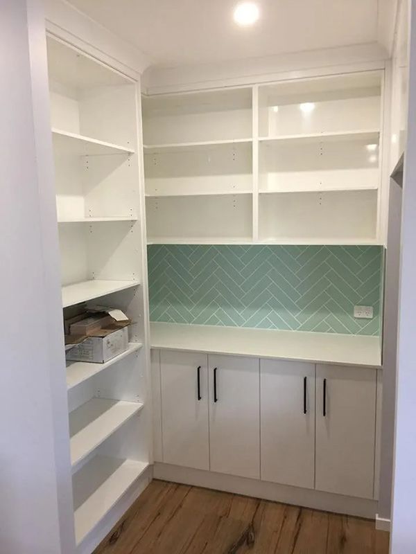 A Kitchen With White Cabinets And Shelves And A Green Tile Wall — Master Cabinets Bundaberg in Kensington, QLD
