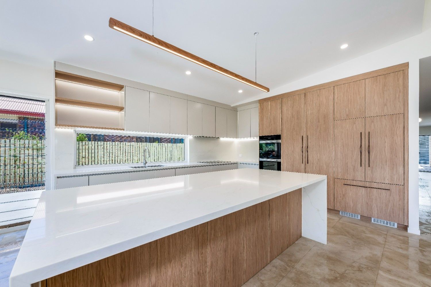 Modern Kitchen With a Large White Island — Master Cabinets Bundaberg in Kensington, QLD