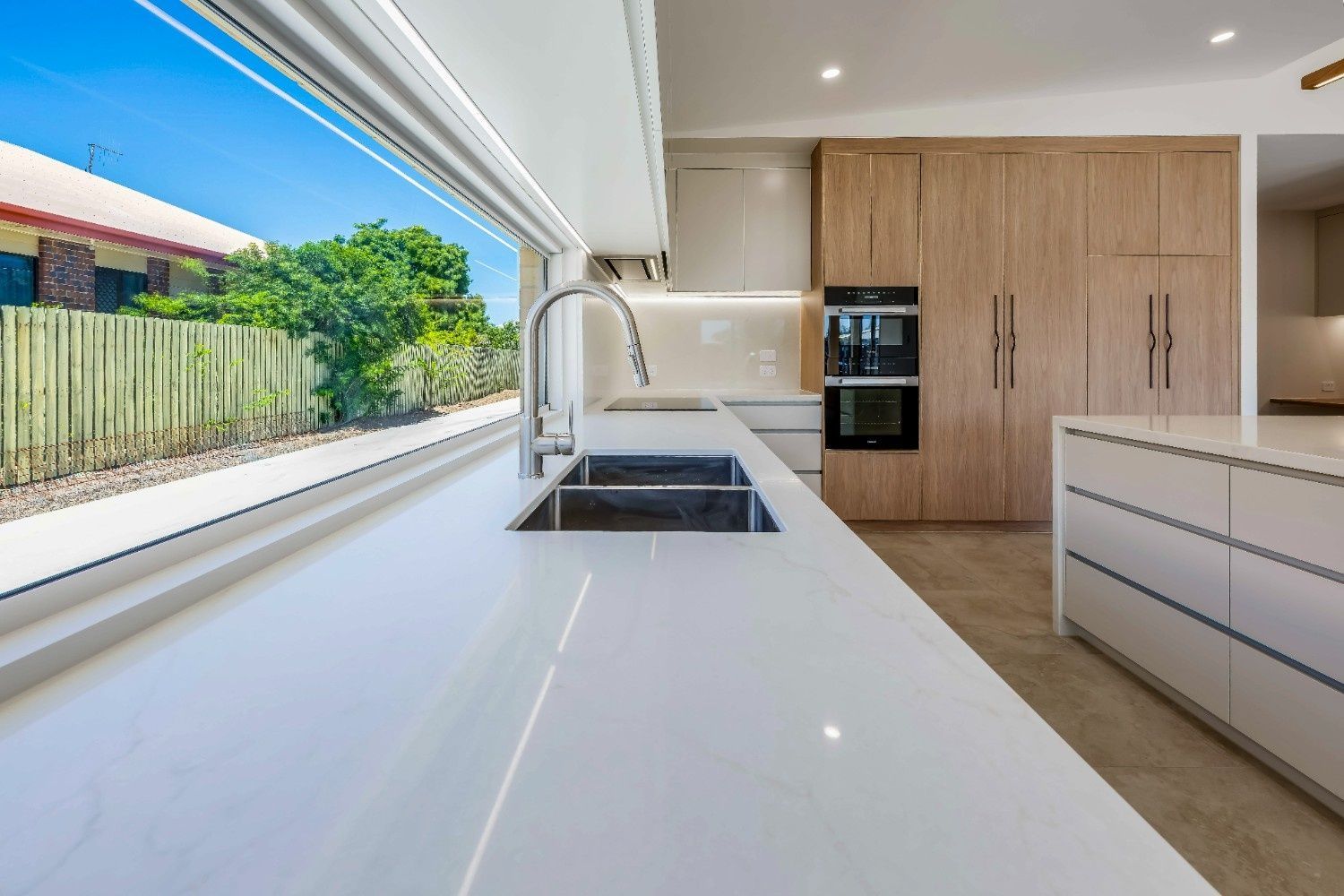 Modern Kitchen With White Island, Wooden Cabinets — Master Cabinets Bundaberg in Kensington, QLD