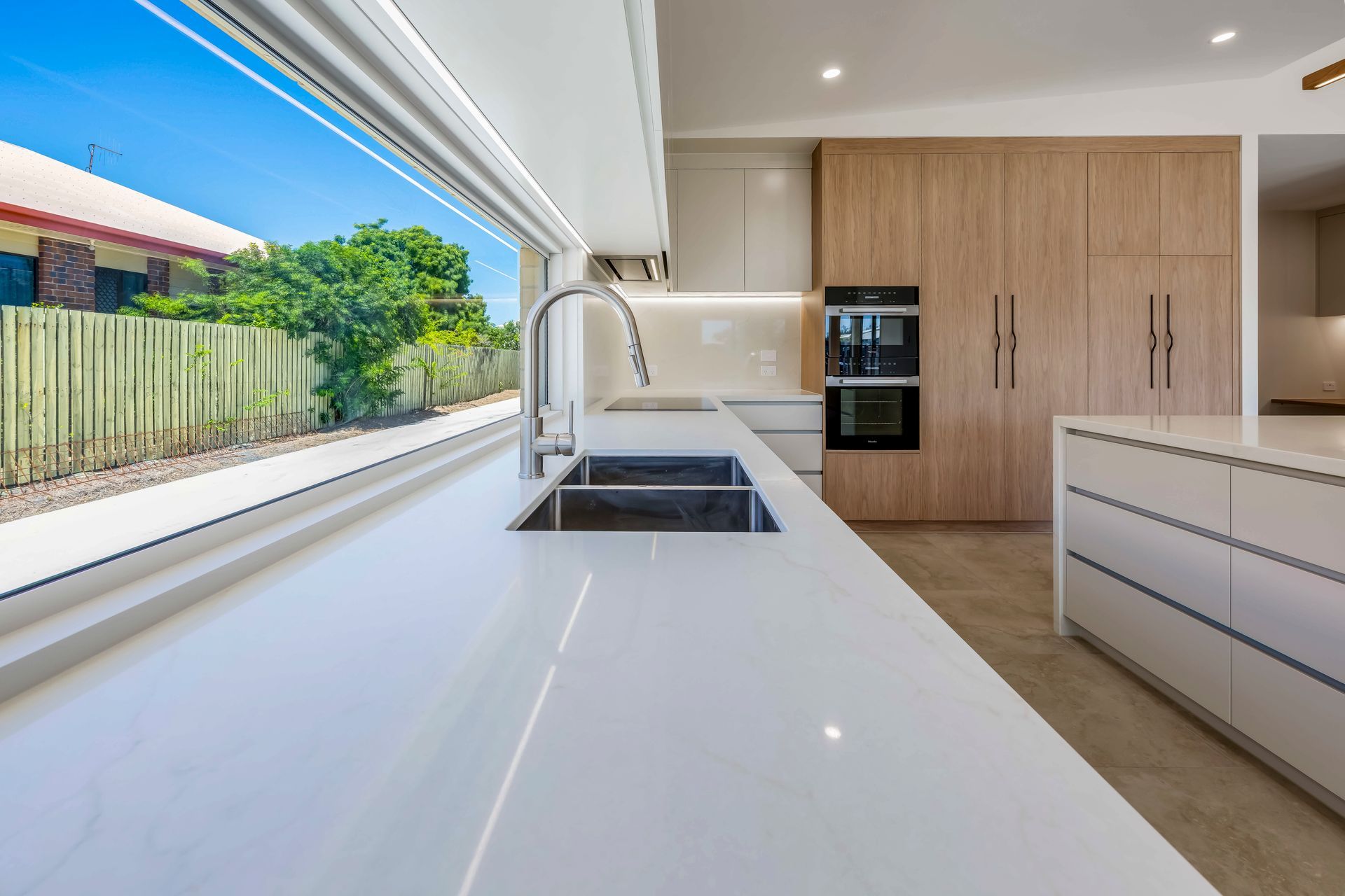 Kitchen with White Marble Benches and Wooden Cupboards, Silver Sink — Master Cabinets Bundaberg in Kensington, QLD