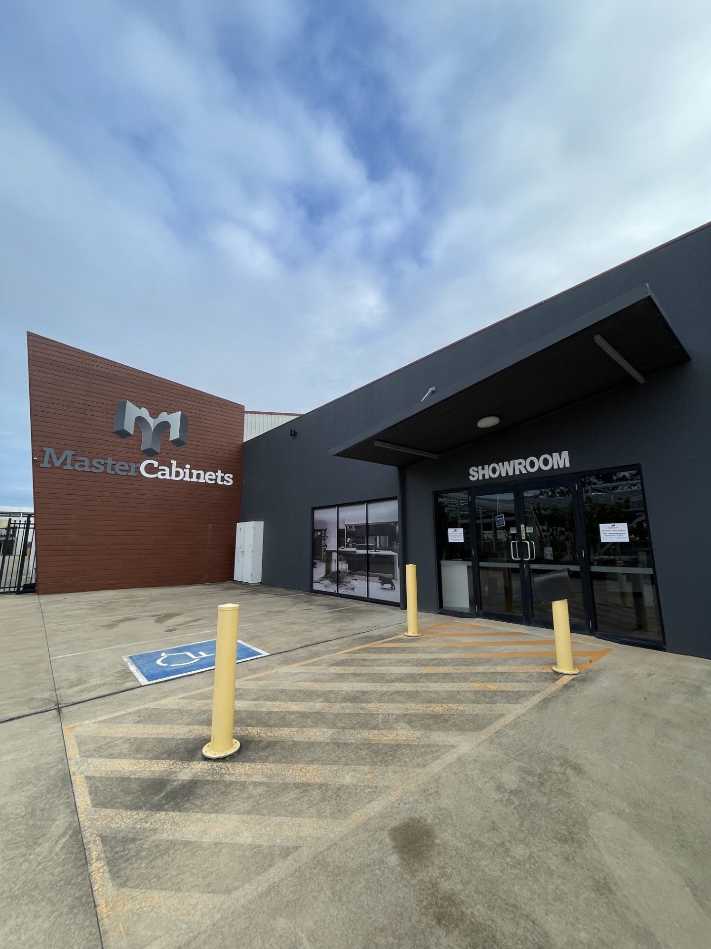 Exterior view of Master Cabinets showroom with accessible parking and cloudy sky.