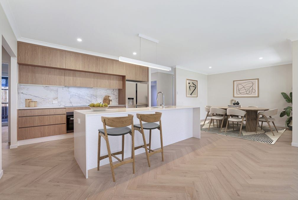 Modern kitchen with light wood cabinets, white countertops, and herringbone tile backsplash.