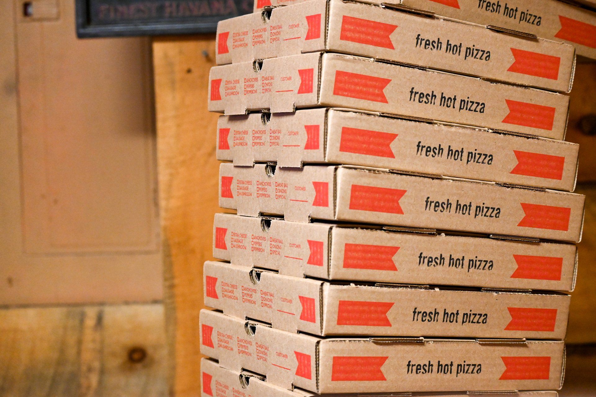 A stack of pizza boxes that say fresh hot pizza