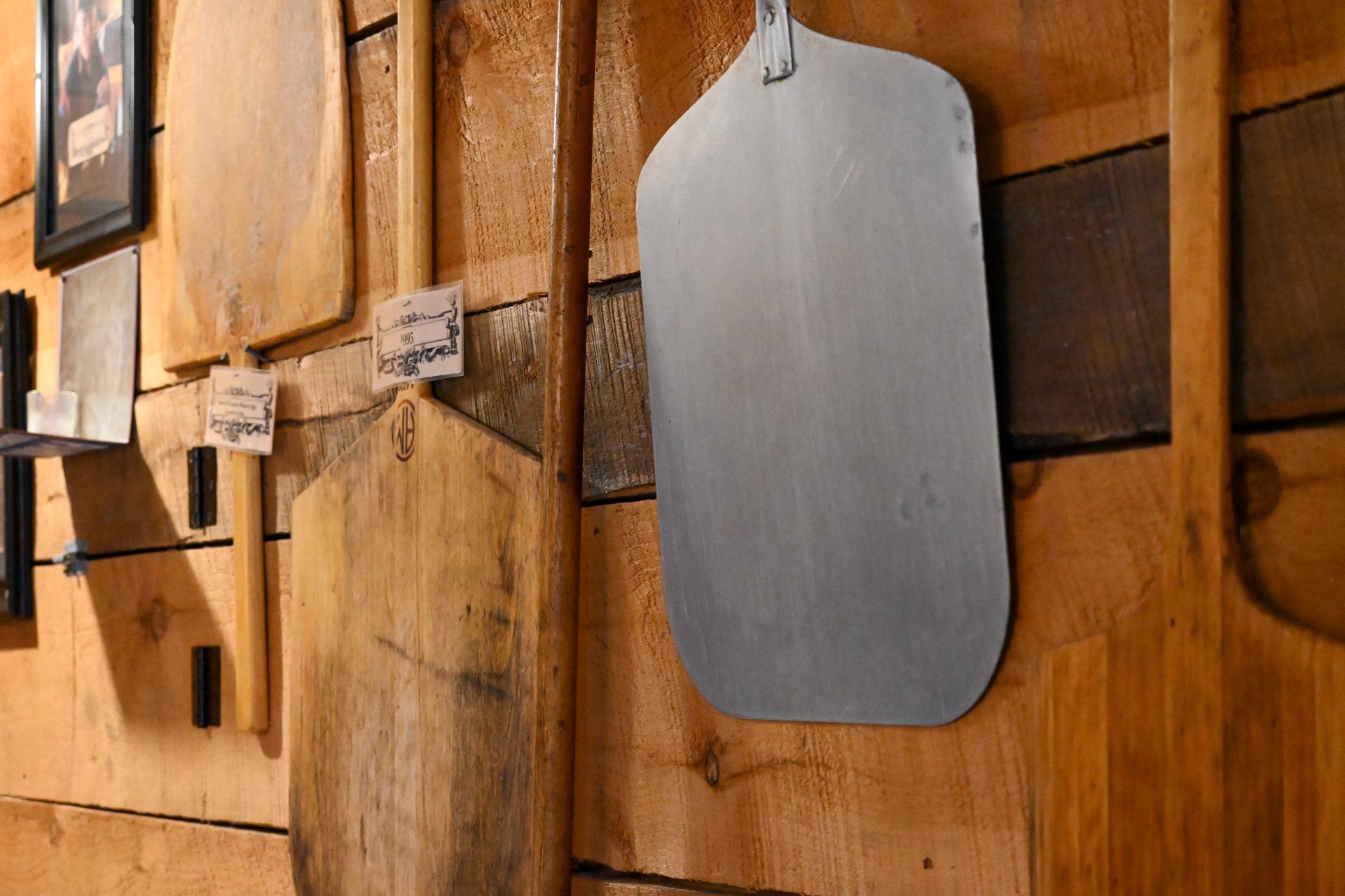 A pizza paddle is hanging on a wooden wall