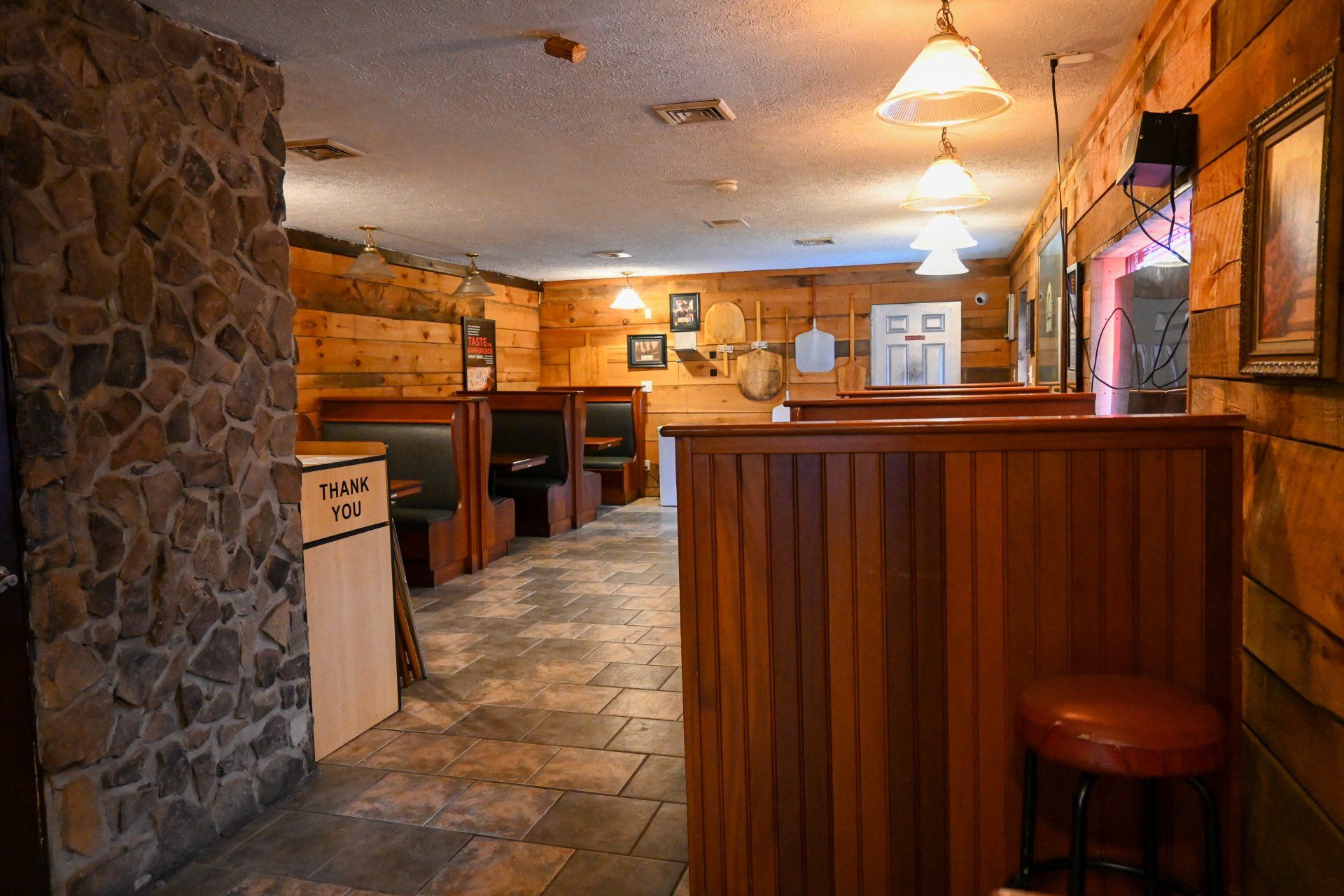 A long hallway in a restaurant with wooden tables and benches.