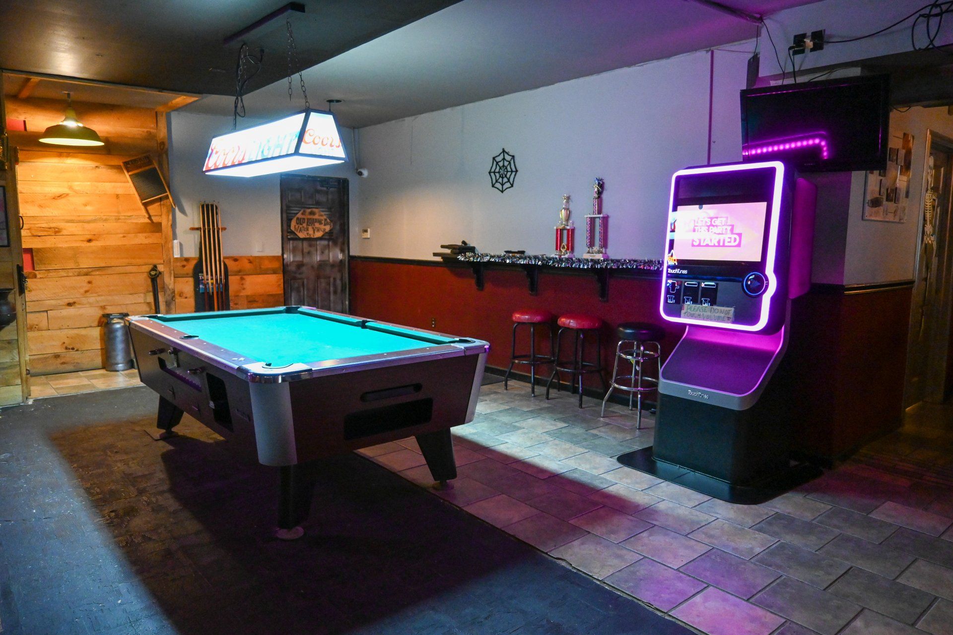 There is a pool table and an arcade machine in the room.